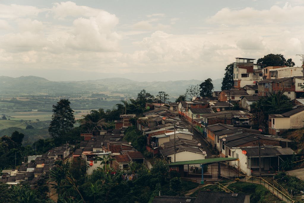 Explore a picturesque hillside town with expansive countryside views under a cloudy sky.